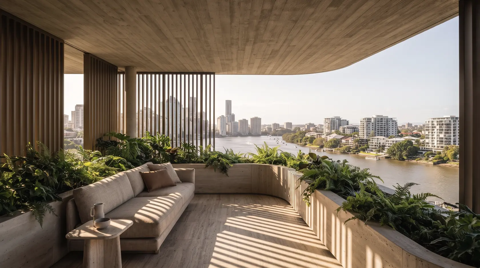 A deep terrace under a board-formed concrete ceiling: a linen sofa and travertine side table, bronze battens striping the floor with shade, ferns along the edge and the Brisbane River curving toward the city.